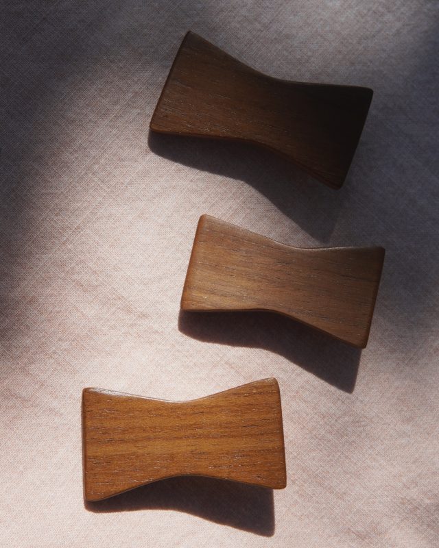 Three wooden bow shaped hair clip on a textured surface