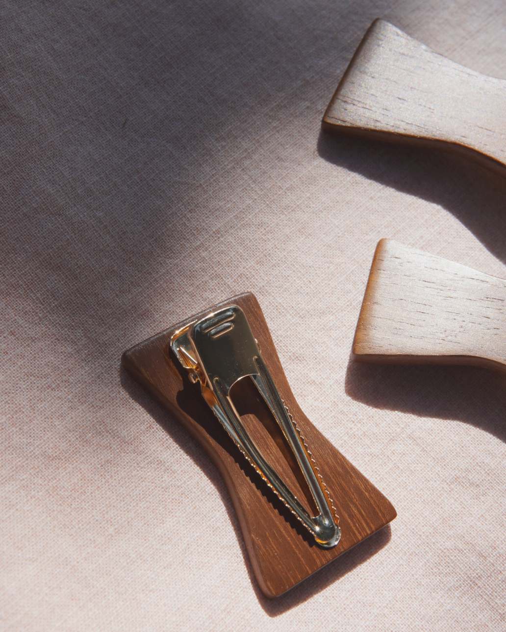 Wooden hair clip with gold clasp on a textured surface.