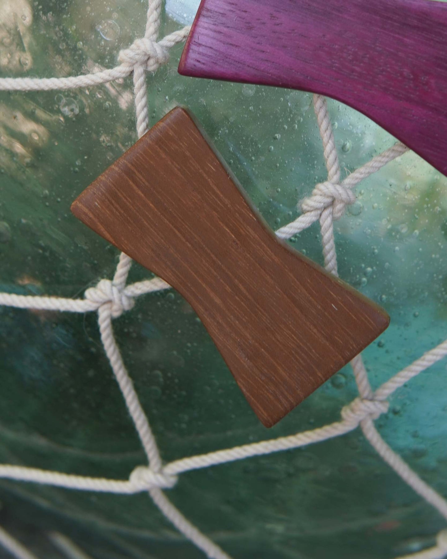 Wooden hair pin on a textured green surface with a purple object partially visible.