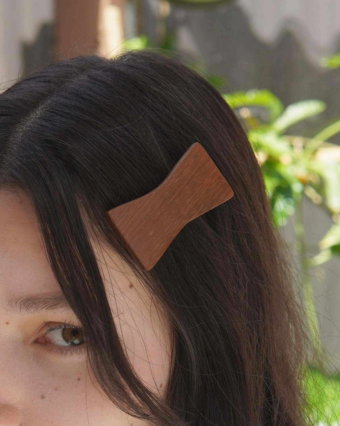 Person wearing a wooden hair clip with a blurred natural background