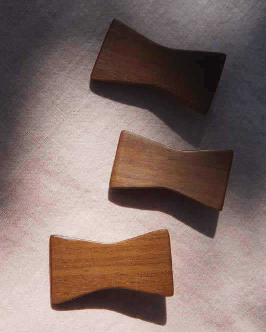 Three wooden bow shaped hair clip on a textured surface